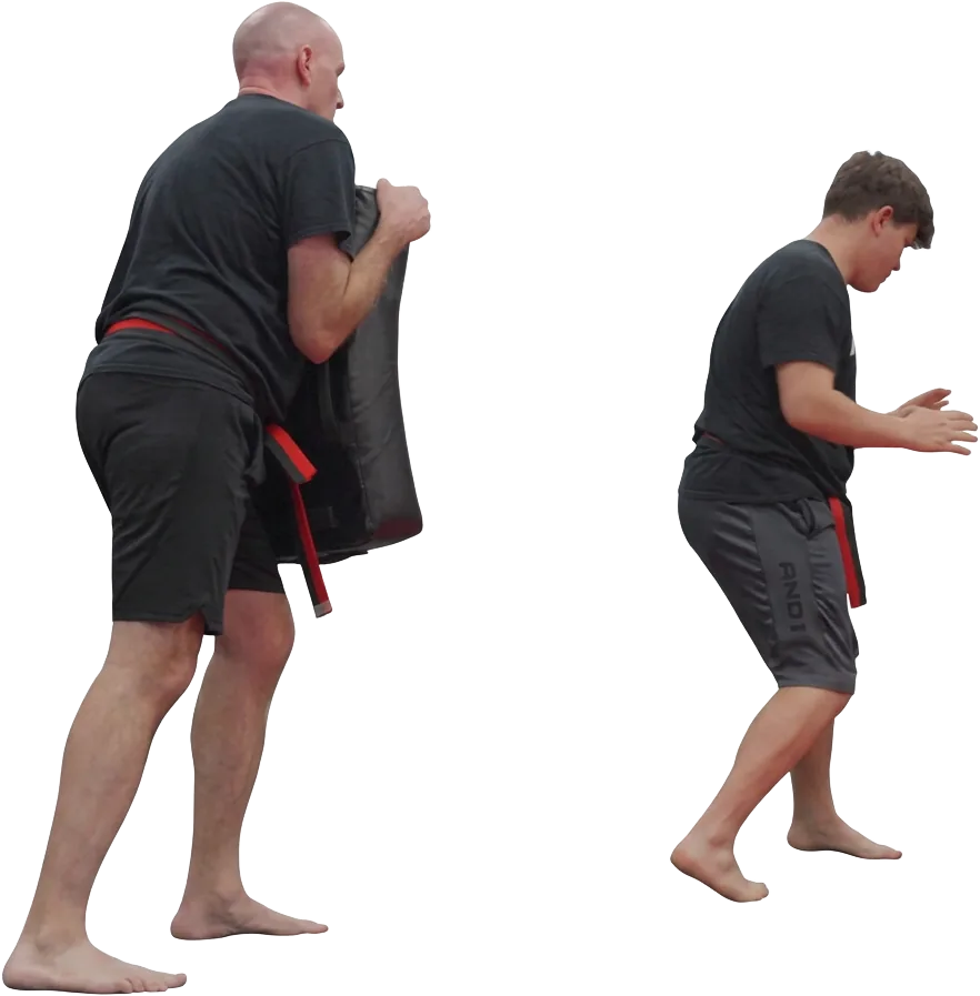 Instructor holding a kick shield while a student steps in during Krav Maga pad work