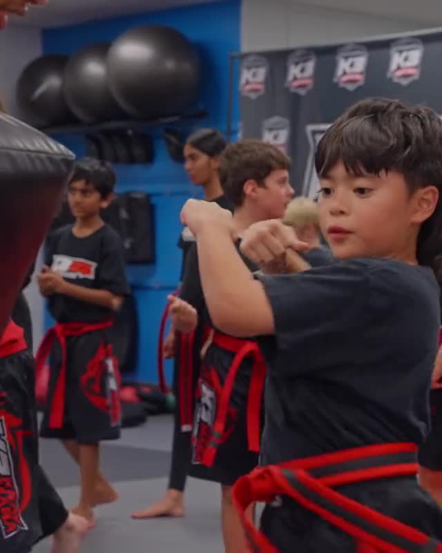 Row of kids in red belts practicing strikes together during a K3 Martial Arts class in Roseville