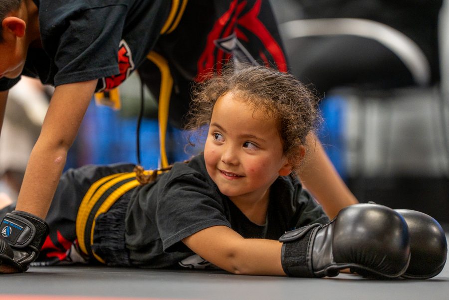 Smiling young student in a blue belt laughing on the mat at K3 Martial Arts in Roseville