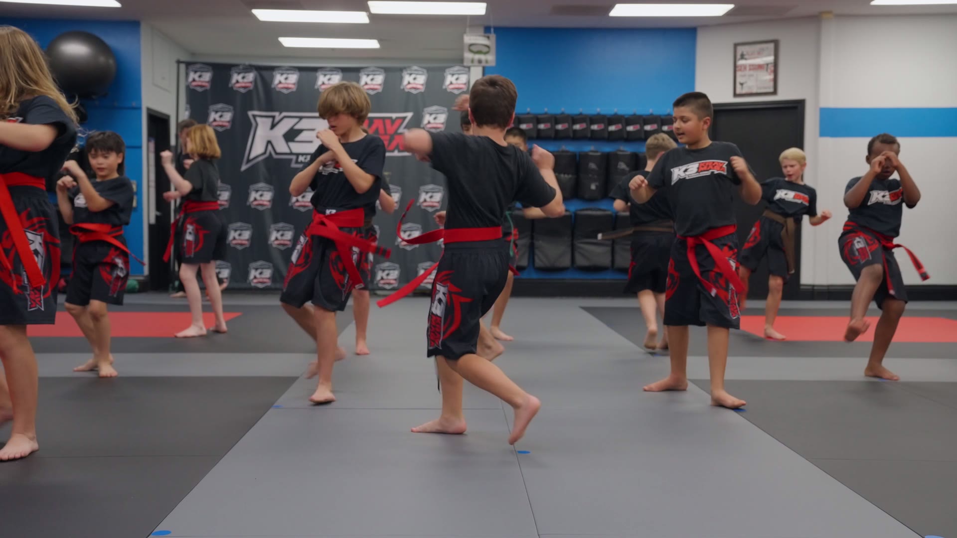 Row of kids in red belts practicing strikes together during a K3 Martial Arts class in Roseville